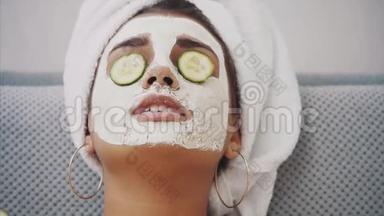 一个漂亮的年轻女人在水疗中<strong>心得</strong>到一个面罩，眼睛里躺着黄瓜。 很开心而且得到很多
